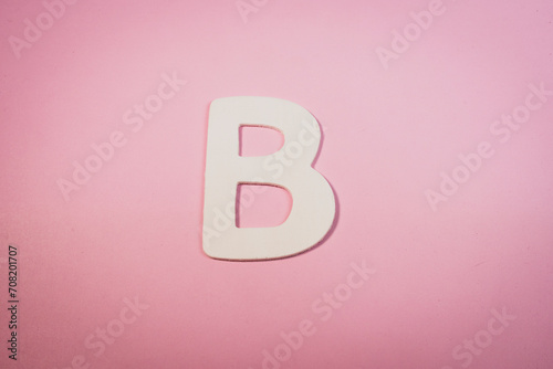 Letter B in wood on a pink background