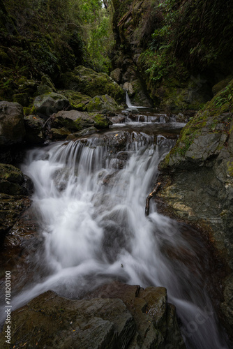 Vertical waterfall background with rocks and trees in a forest