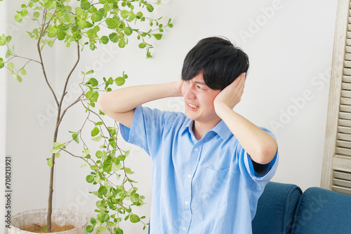 自宅で耳を塞ぐ男性