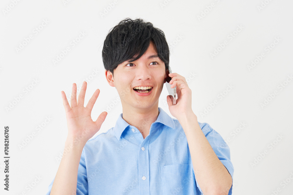 スマートフォンで通話しながら笑顔で驚く男性　白背景