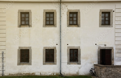 Glass windows on white antique wall of old medieval castle in european suburb close up