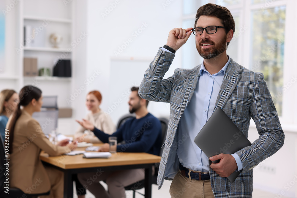 Team of employees working together in office. Stylish businessman with laptop indoors Team of employees working together in office. Stylish businessman with laptop indoors