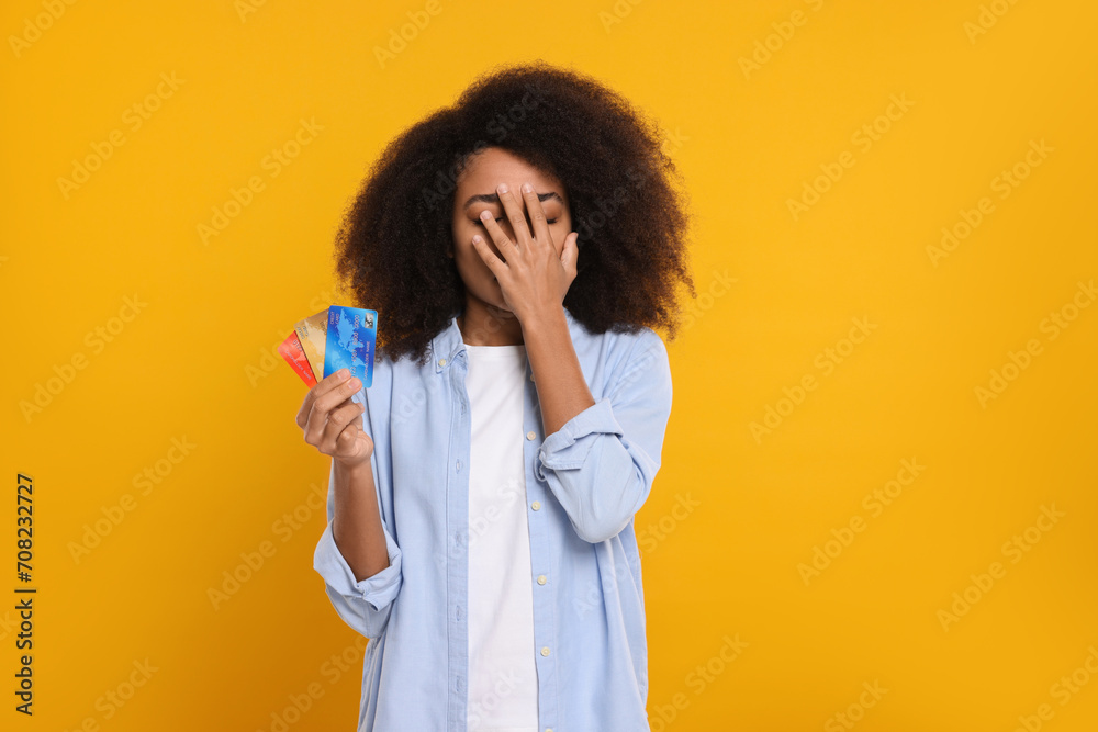 Confused woman with credit cards on orange background. Debt problem Confused woman with credit cards on orange background. Debt problem