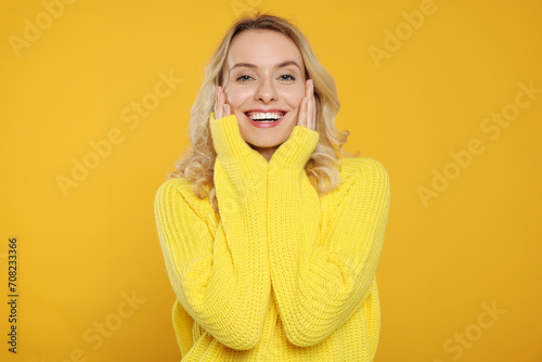 Happy woman in stylish warm sweater on orange background © New Africa