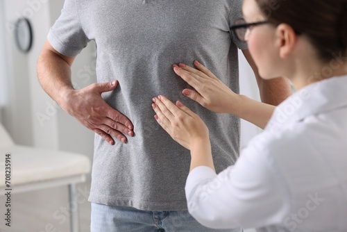 Gastroenterologist examining patient with stomach pain in clinic photo