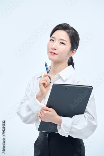 A beautiful Asian woman is making various facial expressions and gestures while holding a document file and a ballpoint pen for business.