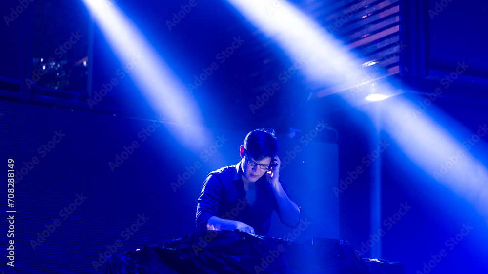 DJ with Turntables at nightclub. Group of diverse young people dancing in night club. Nightlife and disco dance party concept. Fun music festival