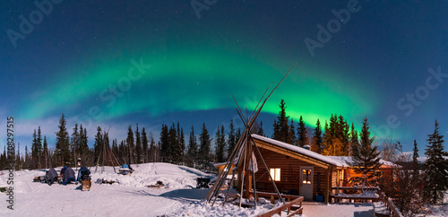 Panorama of Aurora Borealis, Northern Lights, over aboriginal wooden cabin at Yellowknife, Northwest Territories, Canada