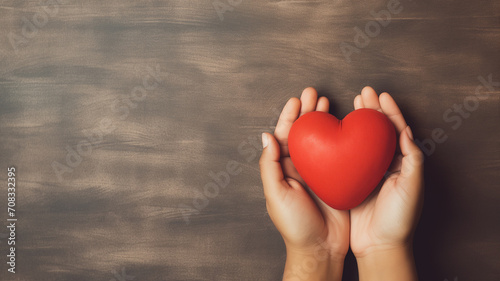 Hand hold red heart on brown background. Concept donation helps find loving health care photo