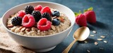  a bowl of oatmeal with berries, raspberries, and almonds on a blue surface.