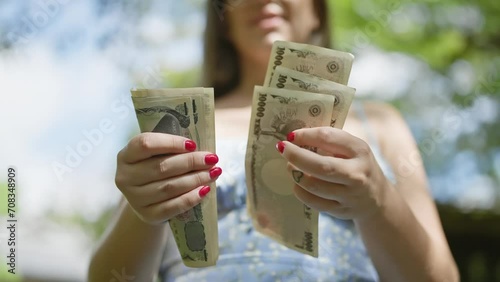 Thrifty young woman counting heap of yen banknotes amidst the lush green of a traditional japanese park, cementing her financial freedom photo