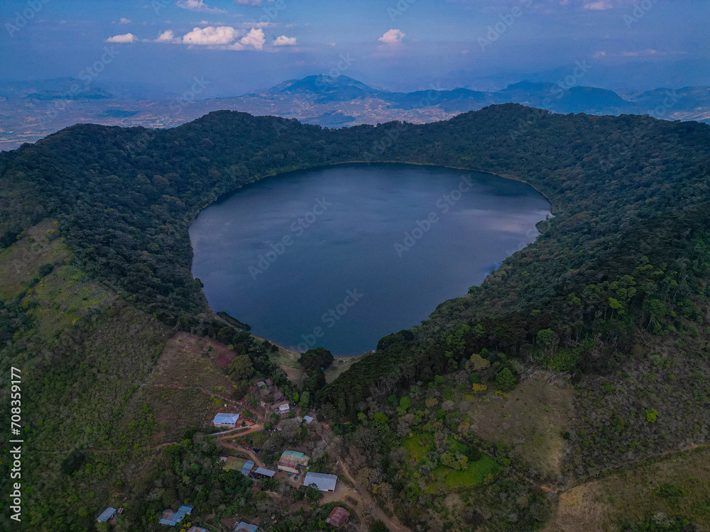 a large body of water surrounded by trees and hills over land
