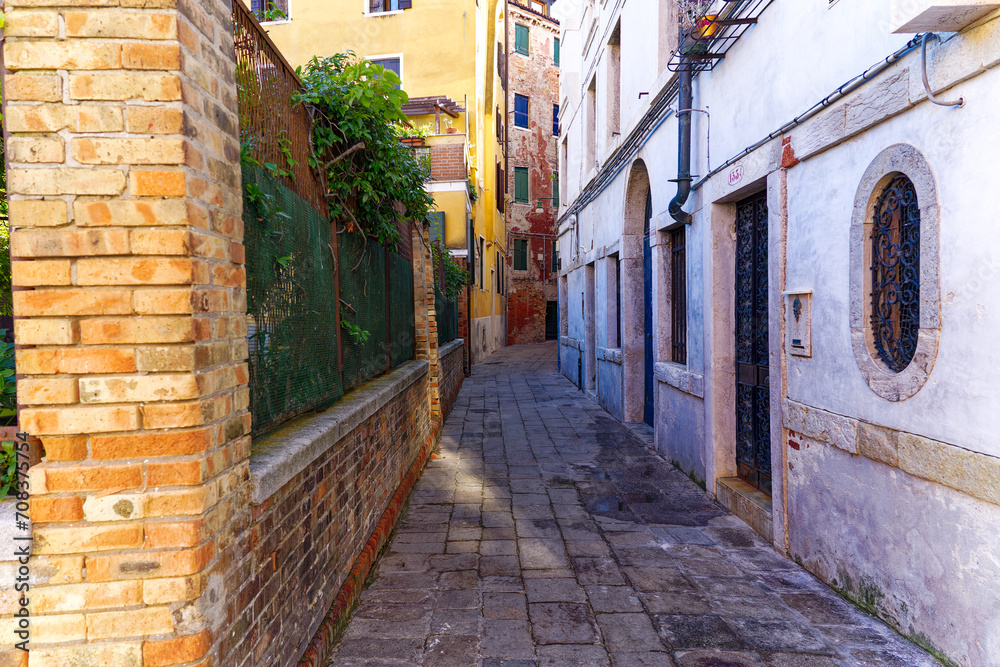 Old town of Italian City of Venice with alley with colorful weathered facades on a summer day. Photo taken August 6th, 2023, Venice, Italy.