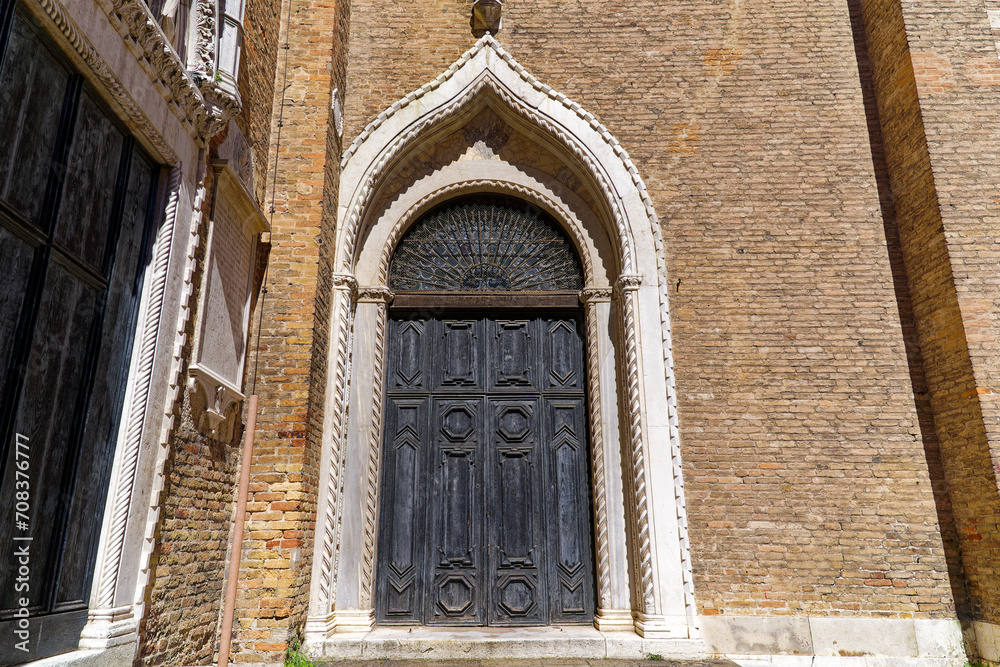 Close-up of wooden door with stone ornaments of church Frari at Italian City of Venice on a cloudy summer day. Photo taken August 7th, 2023, Venice, Italy.