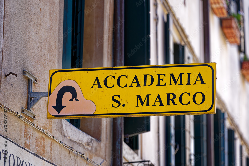 Fototapeta premium Old town of Italian City of Venice with yellow direction sign to art house Accademia and San Marco square on a sunny summer day. Photo taken August 7th, 2023, Venice, Italy.
