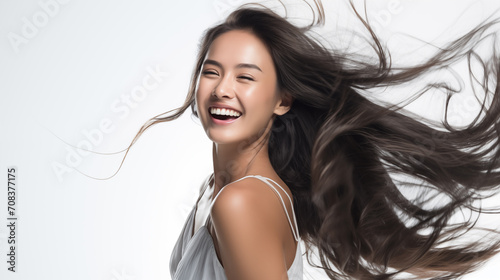 A joyous East Asian woman with her hair flowing freely in the air, capturing a moment of carefree bliss.