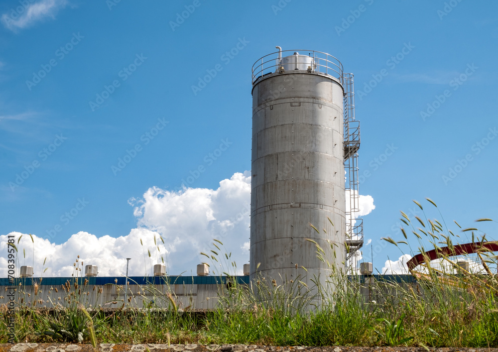 Lone silo tower on blue sky background. Storage of agriculturals or chemicals Lone silo tower on blue sky background. Storage of agriculturals or chemicals