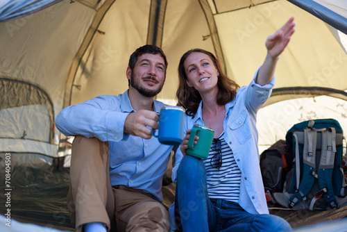 couple drink coffee and talking while they sit inside their tent on a camping trip © SHUTTER DIN