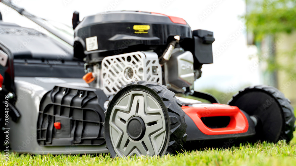 Fototapeta premium lawn mower on a green lawn on a sunny day