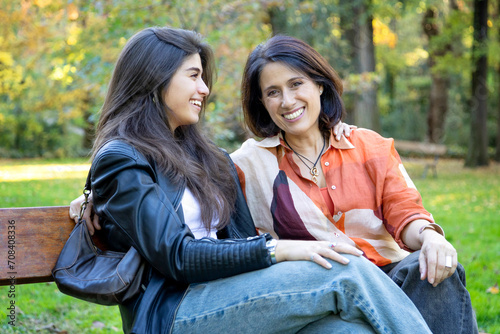 mother enjoying the company of her daughter sitting on a bench happy and smiling
