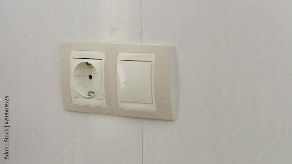 Man plugging in power cord into wall socket Man plugging in power cord into wall socket