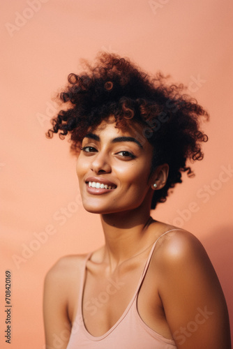 Beautiful african american woman with curly hair smiling at camera isolated on orange