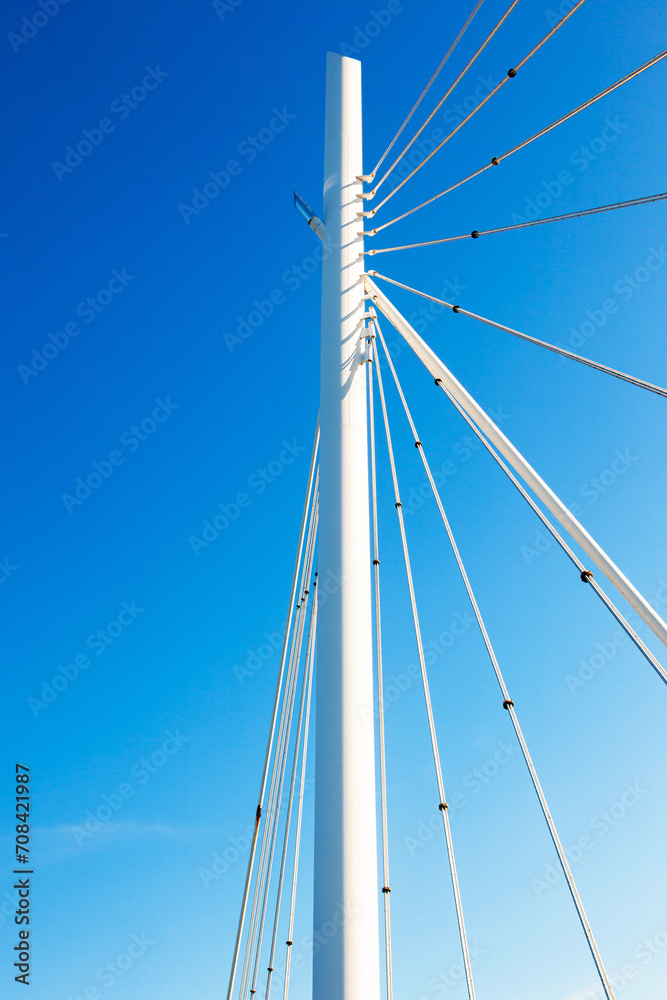 White vertical pillar of a bridge with steel braces, against a background of blue sky, view from below. White vertical pillar of a bridge with steel braces, against a background of blue sky, view from below.