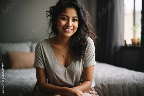 happy mexican young woman sitting on the bed 