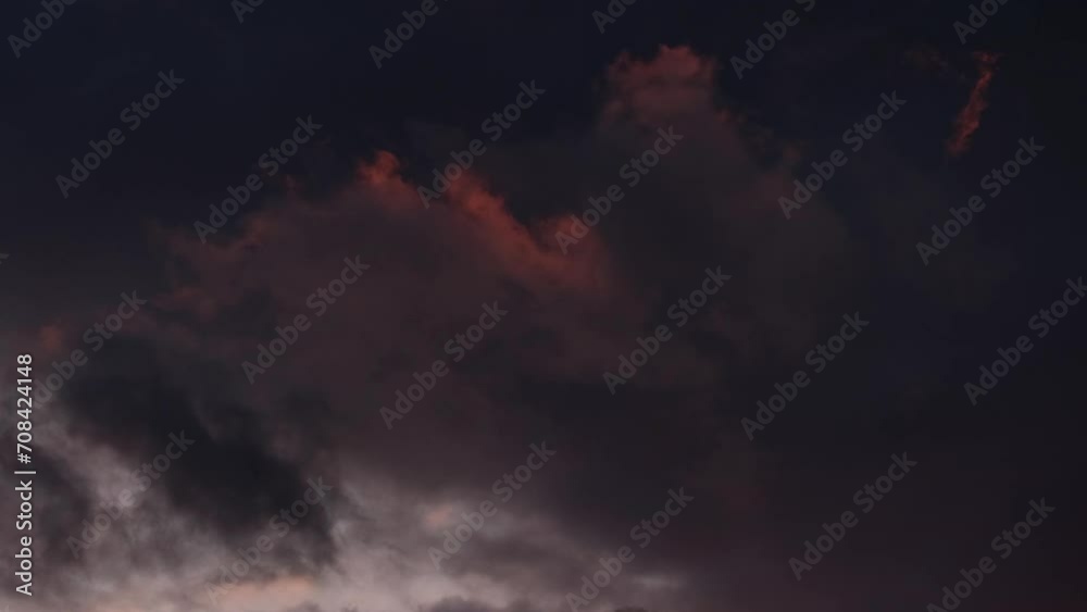 Slow motion close-up of fluffy clouds in pink sunset lights moving against the dark blue stormy sky. Magnificent dramatic nature. Last rays of the sun. Relaxing or meditative colourful cloudscapes.