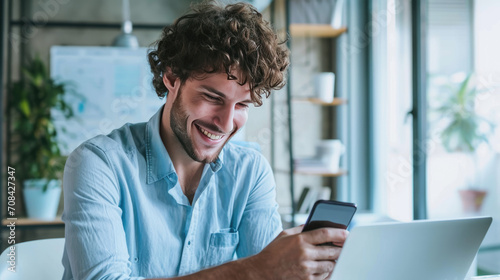 Happy man using a smartphone during his work in the office photo