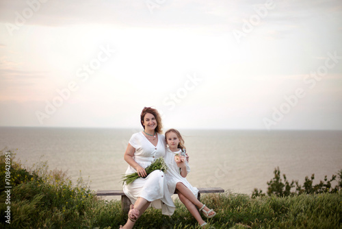 Mother with little daughter sitting on a bench at a mountain top