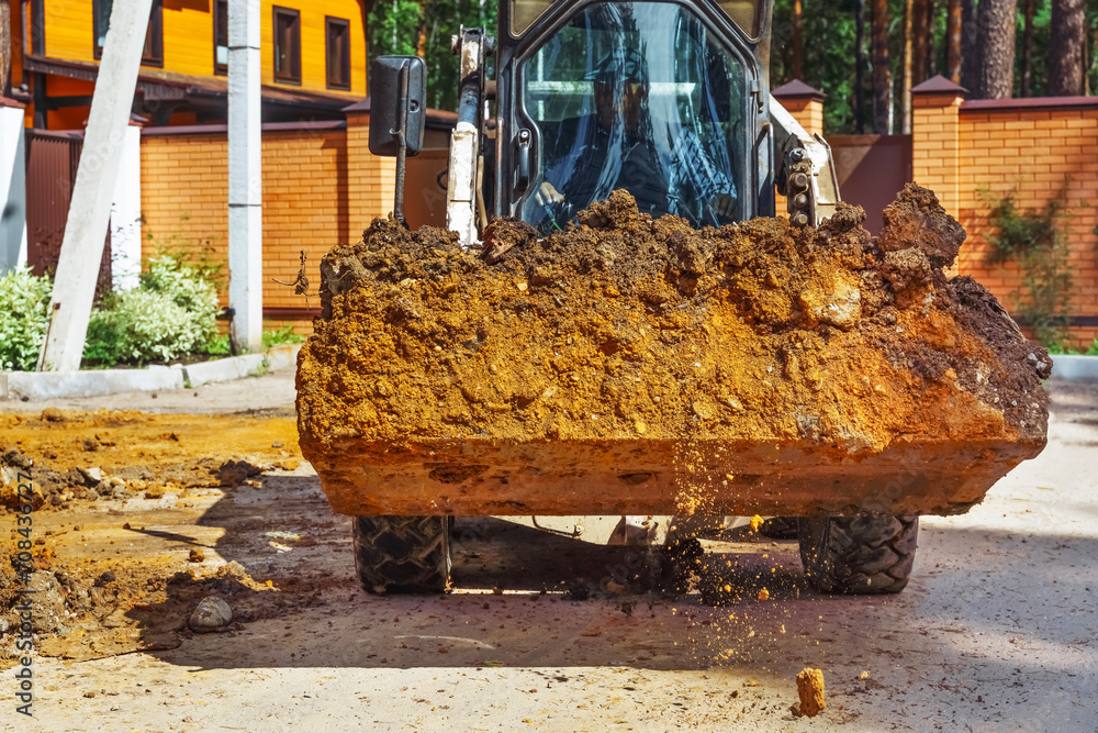 Fototapeta premium Loading soil with an excavator at a new construction site. Backhoe Digging at Construction Site.