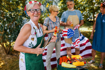 Elderly people are making barbeque, drinking beverages, making memories, and laughing.