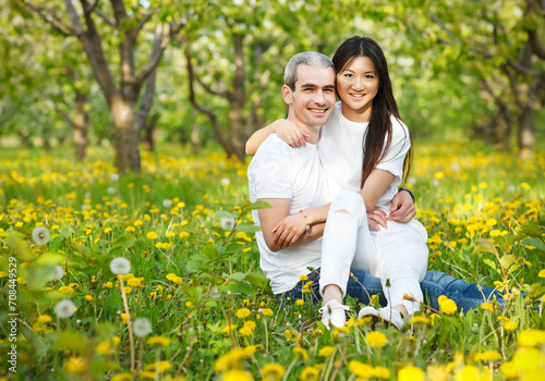 Young loving couple at the green grass with dandelion