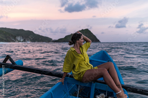 Woman traveler relaxing at dusk on a traditional boat in Indonesia, summer mood photo