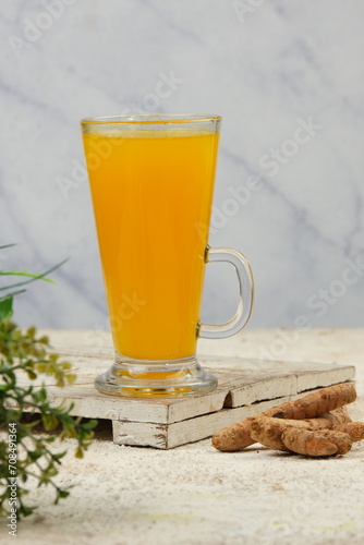 indonesian traditional herbal drink for women.jamu kunyit asam  with the basic ingredients of turmeric and tamarind and other herbs.heaps of turmeric in a bamboo basket as a background photo