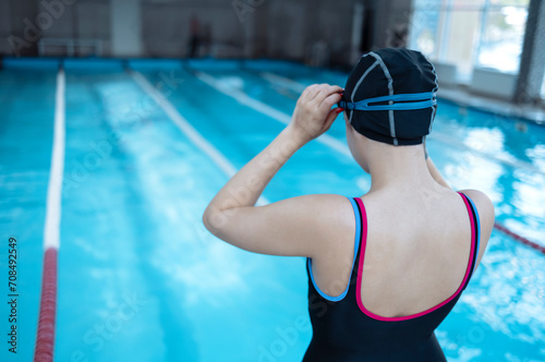 Young swimmer wears a swim cap and puts away goggles © Dasha Petrenko