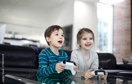 Joyful children with game controllers play video games at home