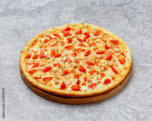 Homemade Italian style pizza with cheese, chicken and tomatoes close-up on a wooden board on the table. Horizontal