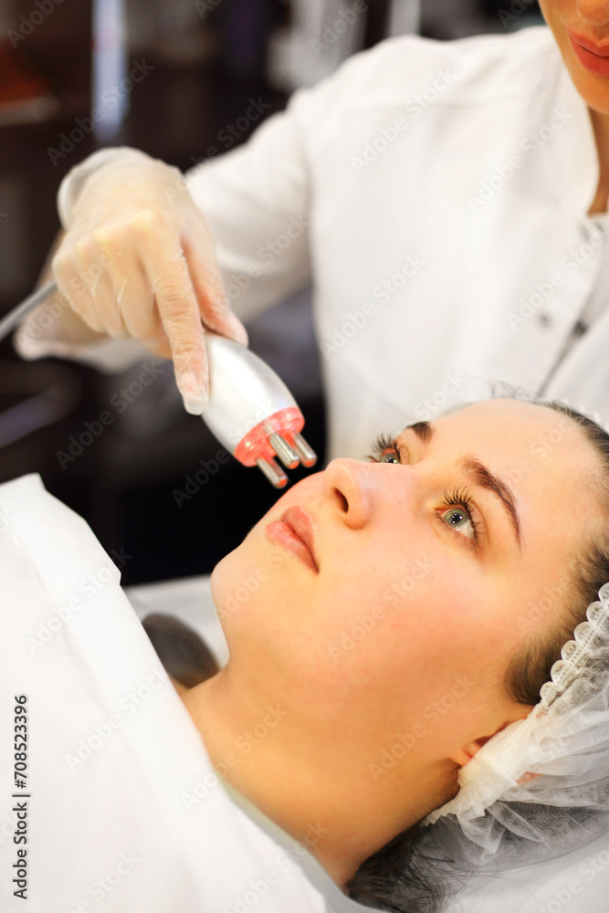 Naklejka premium Crop beautician using machine for radiofrequency lifting
