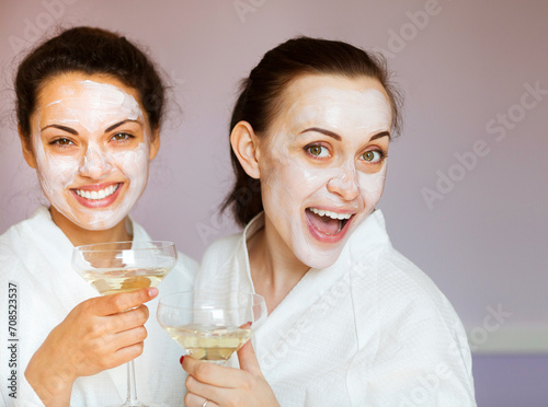 Young happy female friends drinking champagne in spa