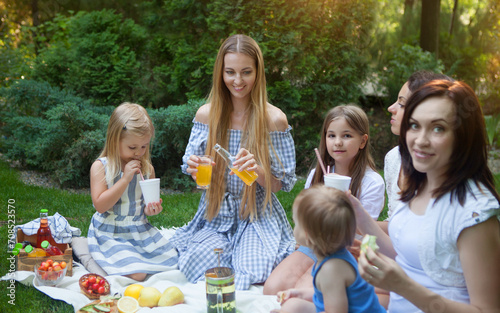 Three happy young mothers and daughters having picnic