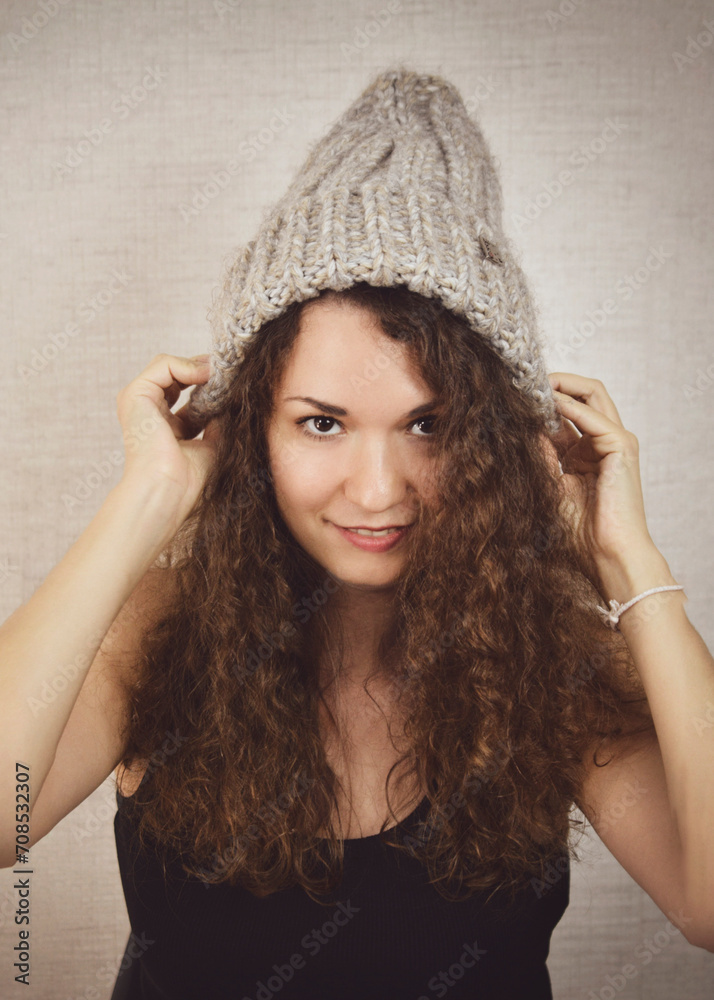 Portrait of a beautiful girl in a knitted gray hat in close-up. Girl with curly hair. Portrait of a beautiful girl in a knitted gray hat in close-up. Girl with curly hair.