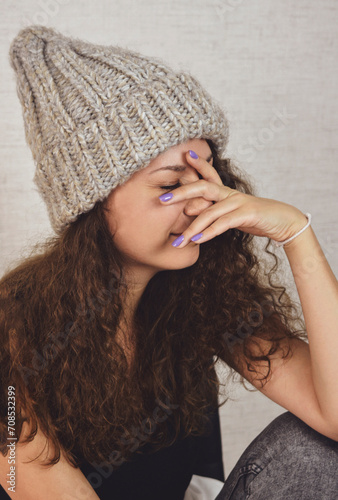 Young girl hides her face under a knitted hat. Funny cute photo.