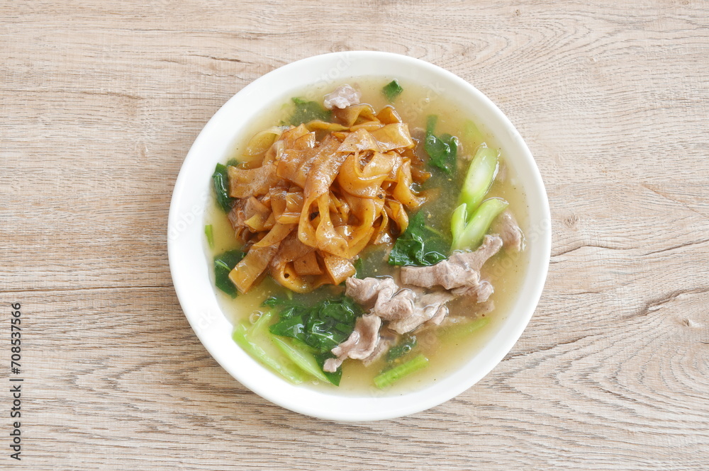 fried large noodle with slice beef meat and Chinese kale dressing gravy sauce on plate fried large noodle with slice beef meat and Chinese kale dressing gravy sauce on plate