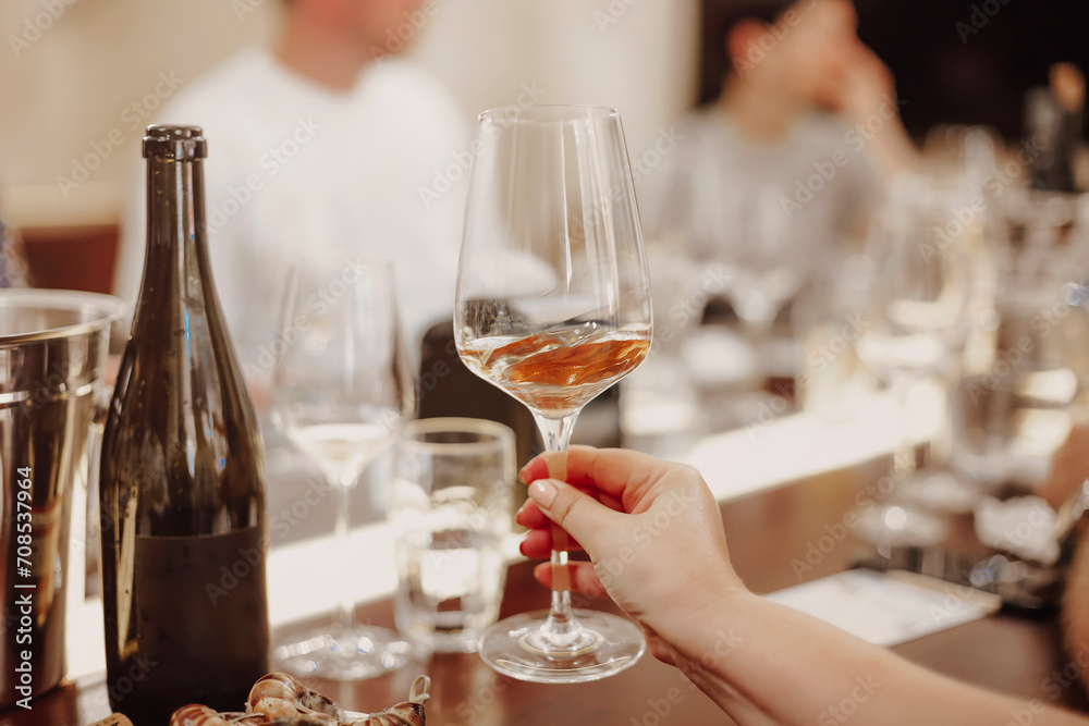 Glasses with different types of wine and human hands holding wine glasses in the background