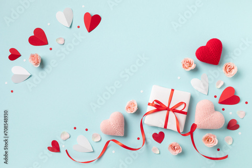 Valentine or mother day festive composition with gift or present box  rose flowers and red pink hearts on pastel blue background top view. Flat lay greeting card..