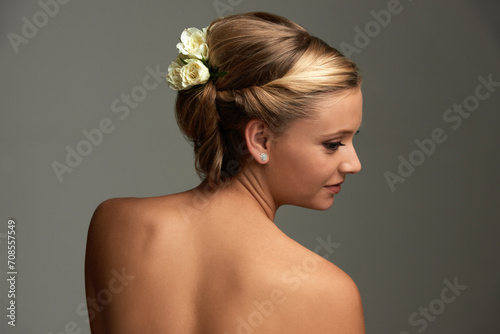 Shine, skincare and woman with cosmetics, beauty or luxury on a grey studio background. Person, girl or model with aesthetic, hairstyle or grooming with flowers, healthy skin or dermatology with updo