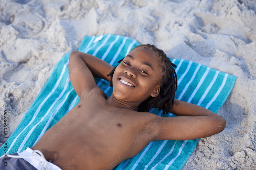 Naklejka premium Portrait, beach sand and towel with child to relax and summer holiday with sunshine in nature. Black teenager, face and smile for leisure on vacation, cape town and seaside for wellness in outdoor