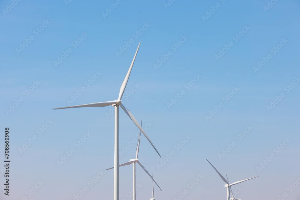Field of wind turbines with motion blur on their blade using long exposure during sunny day and blue sky